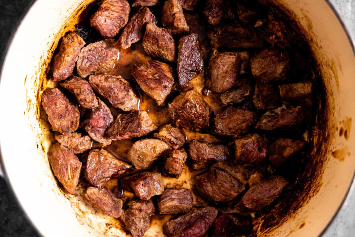 Beef tips searing in a skillet.