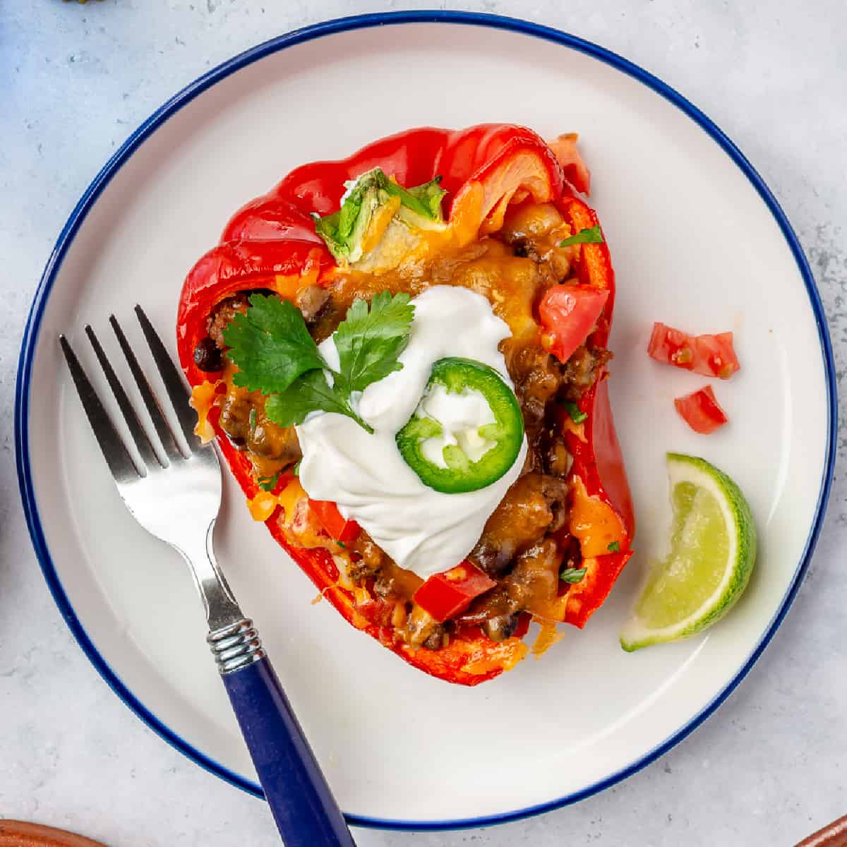 Taco stuffed bell pepper served on a plate with a fork. 