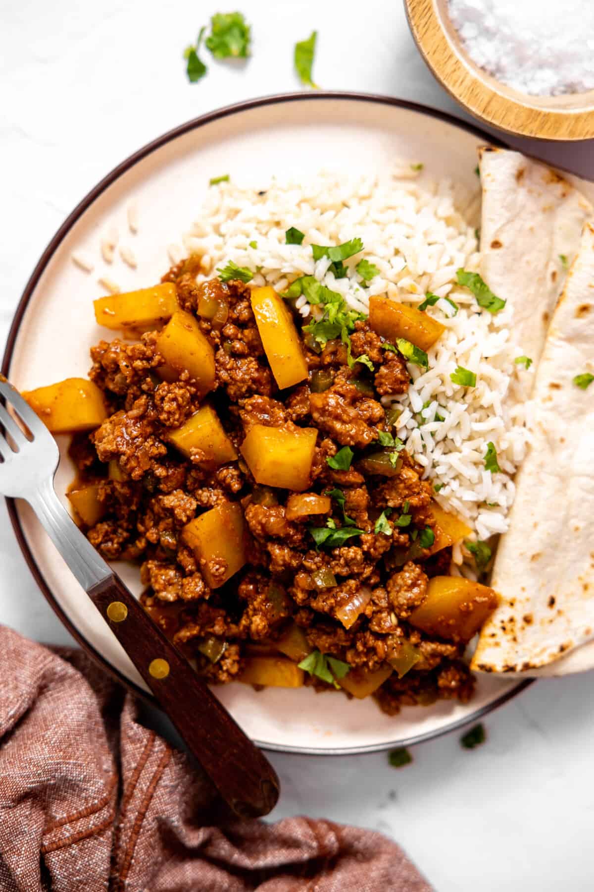 Plate with rice and ground beef picadillo with a flour tortilla.