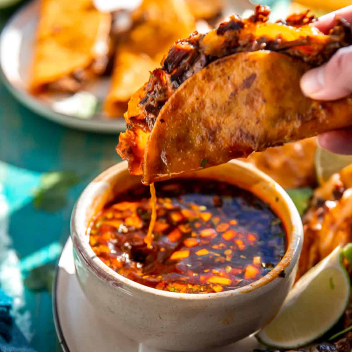 Quesabirria taco being dipped into consommé.