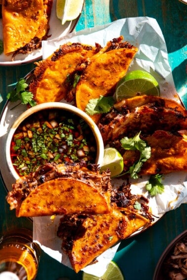 Plate filled with birria tacos and a bowl of consommé.