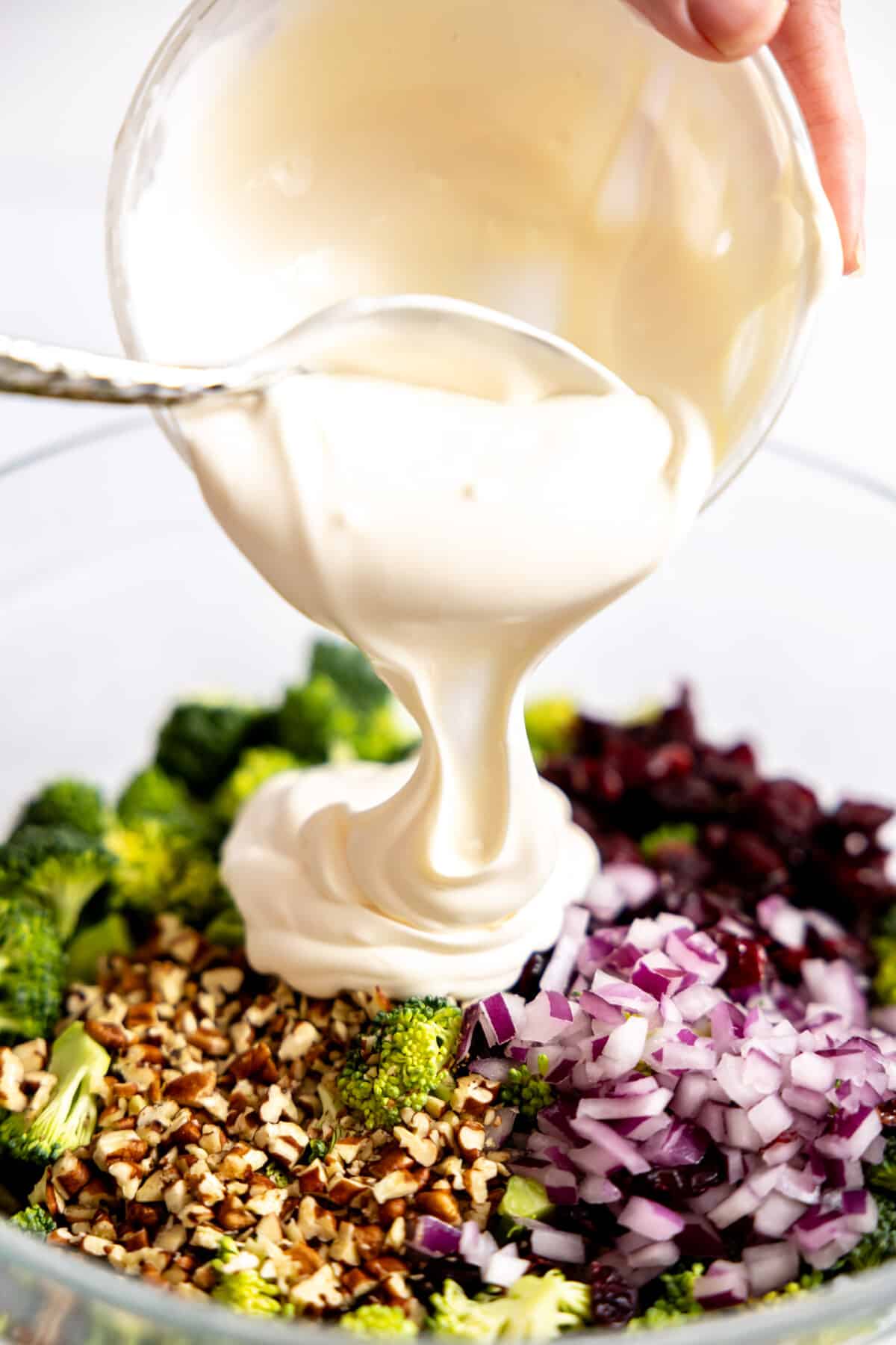 Dressing being added to broccoli salad. 