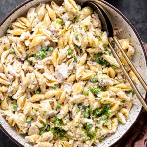 Bowl of tuna pasta salad with serving spoons.
