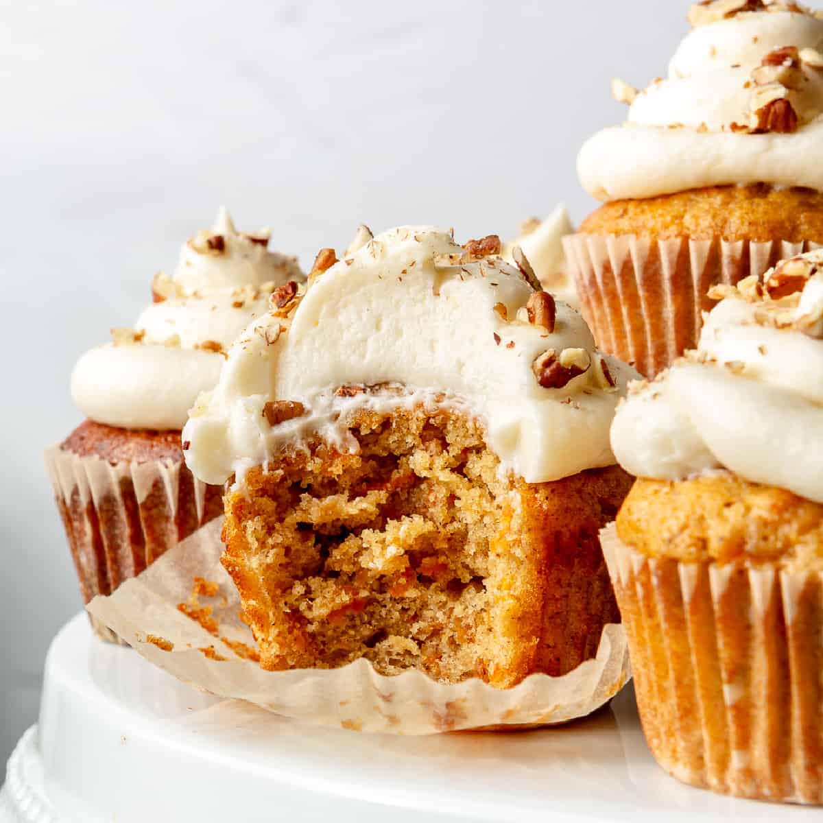 Carrot cake cupcakes on a white cake stand.