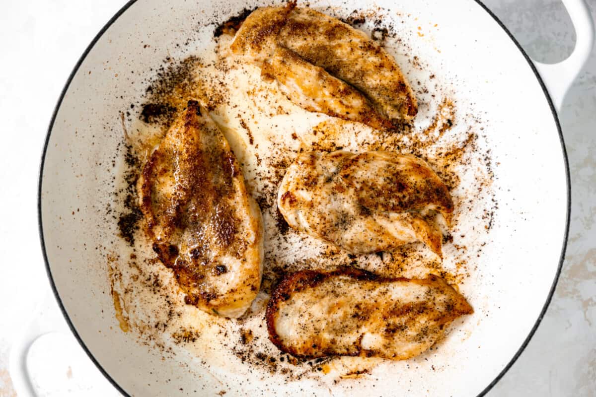 Chicken breasts seared in a skillet. 