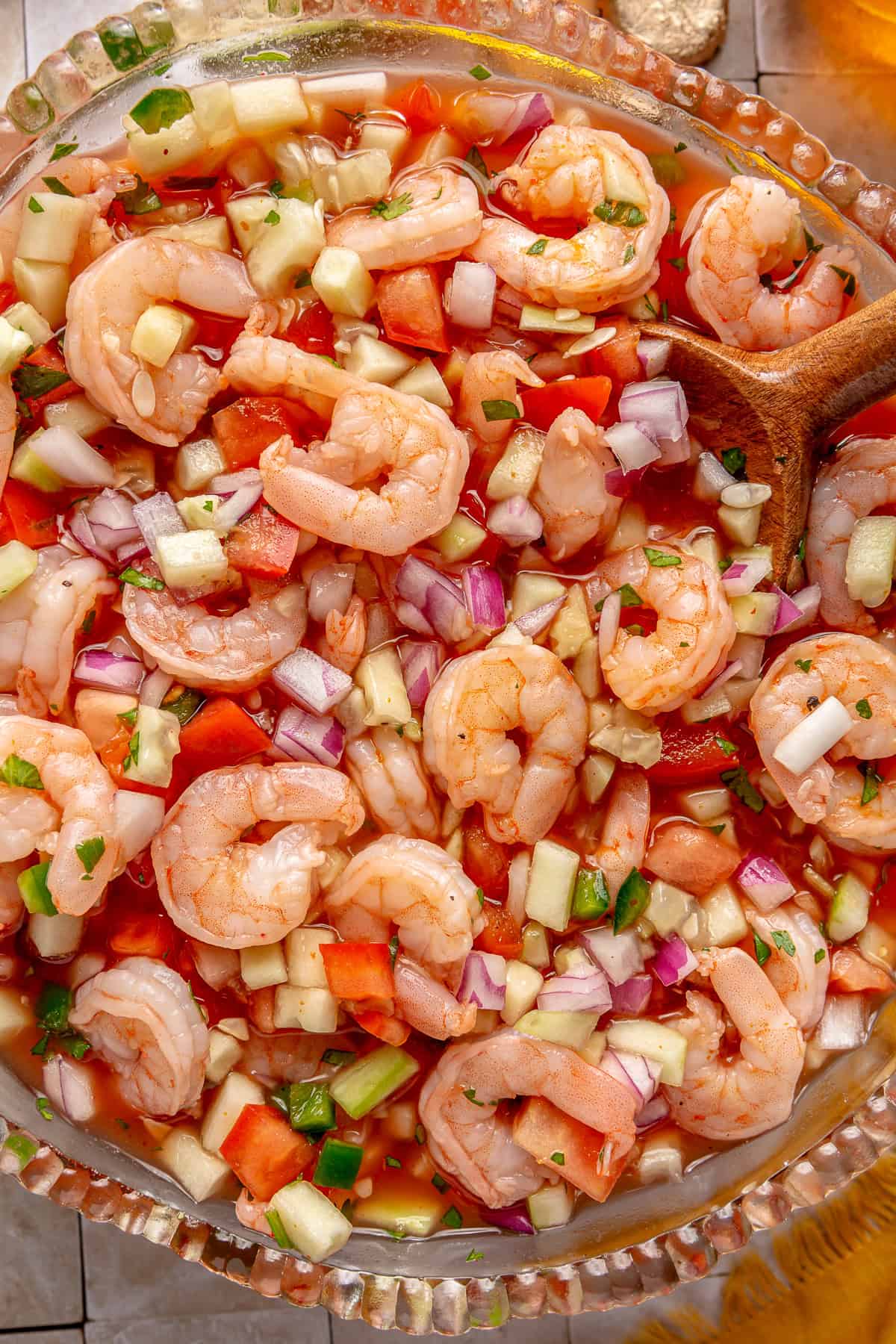 Mexican Shrimp cocktail in a large glass bowl with a wooden spoon.