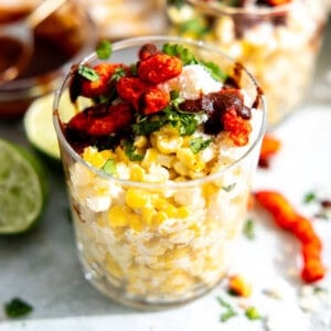 Esquites, Mexican street corn in a cup, topped with queso fresco, hot Cheetos, fresh cilantro and a chile sauce.