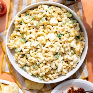 Macaroni salad in a bowl with soda being poured on the side.
