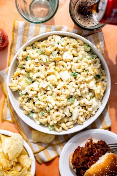 Macaroni salad in a bowl with soda being poured on the side.