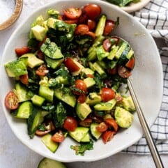 Bowl with avocado tomato and cucumber salad with a cilantro lime vinaigrette.