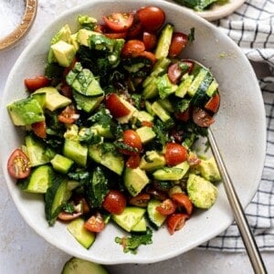Bowl with avocado tomato and cucumber salad with a cilantro lime vinaigrette.