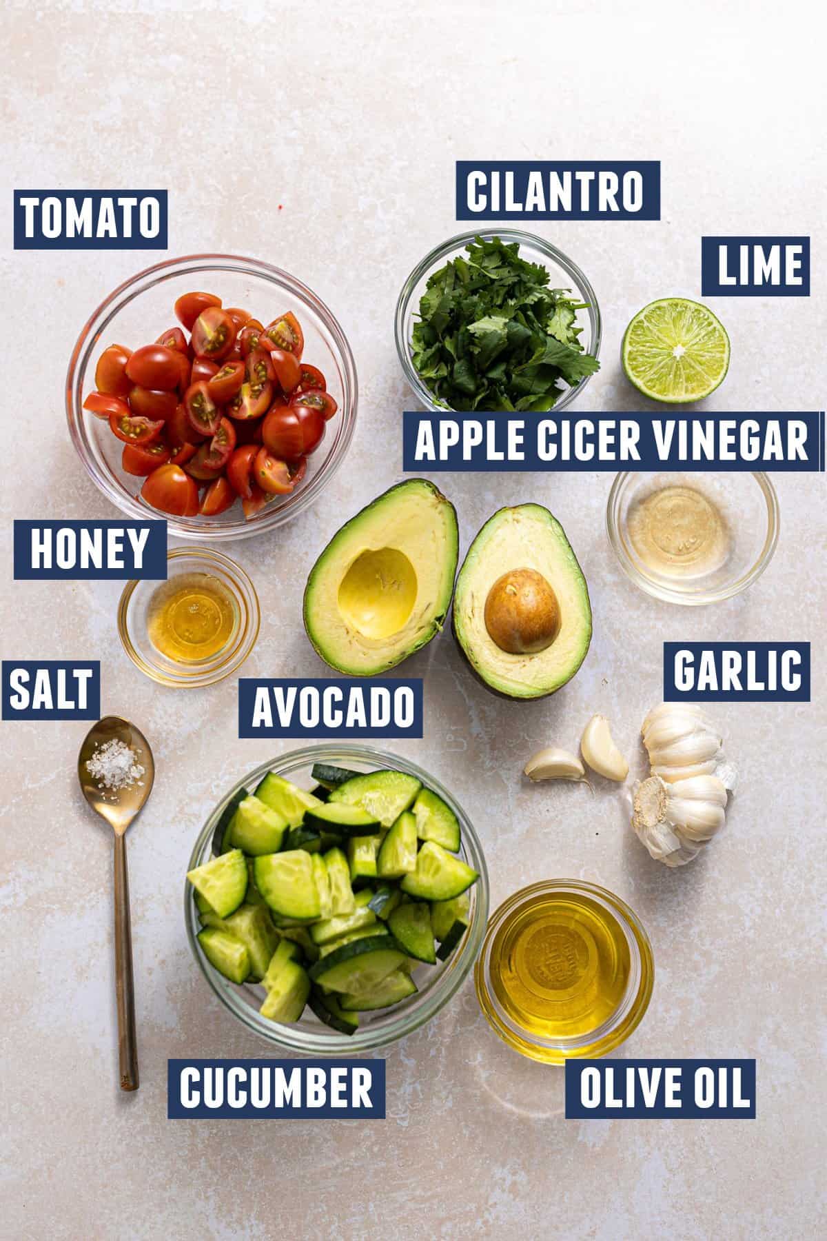 Ingredients needed to make Avocado, Tomato, and cucumber salad laid out.