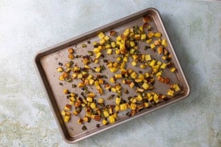 Potatoes and bell peppers on a baking sheet.